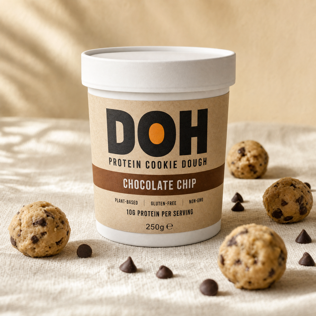 DOH Snacking Dough — Classic Chocolate Chip tub on warm cream linen with scattered cookie dough balls